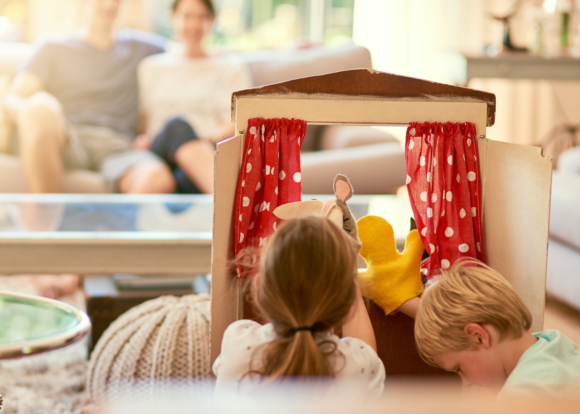 Cropped shot of two siblings performing a puppet show for their parents at home